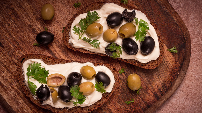 Overhead view of cream cheese and olives on toast