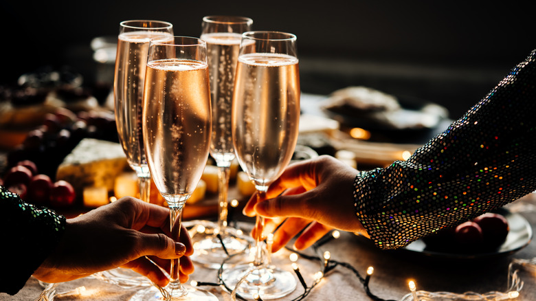 Hands clink champagne glasses on New Year's Eve