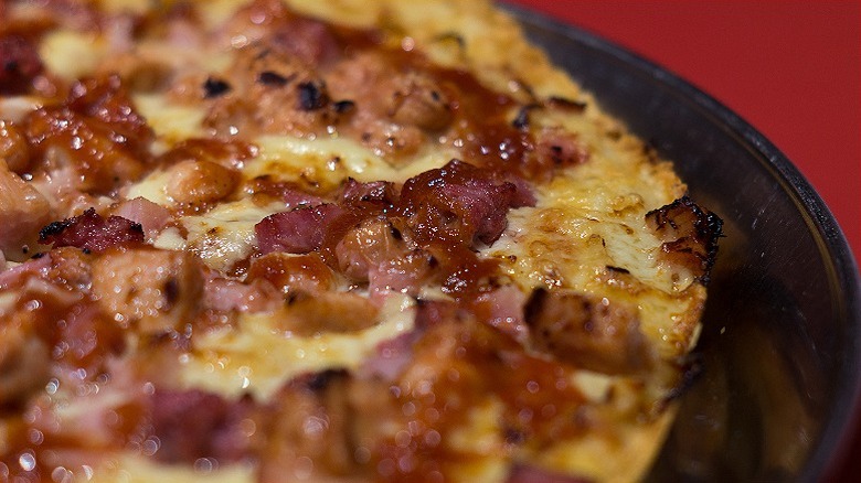 A close-up of a pizza with cheese and a variety of meats