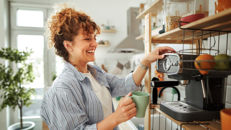 Young beautiful smiling woman making coffee in a domestic kitchen