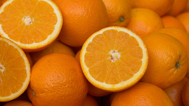 A pile of navel oranges with three halves on top