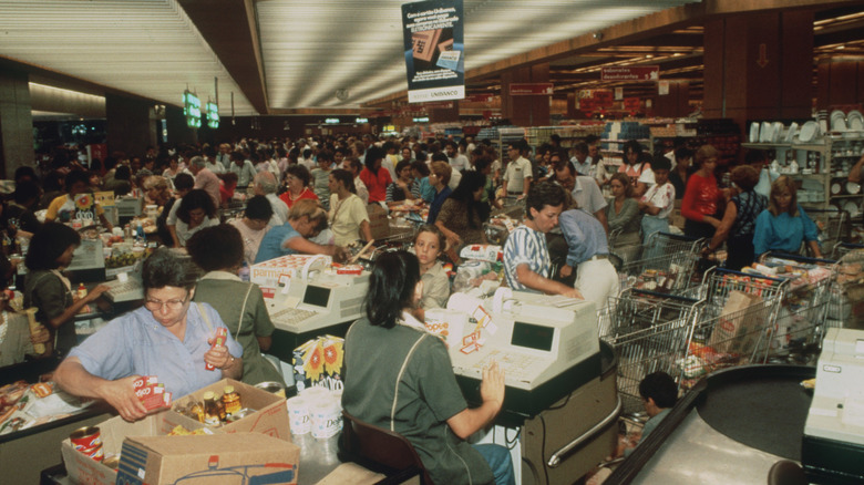 A crowded row of checkout lines in a 1980s superstore