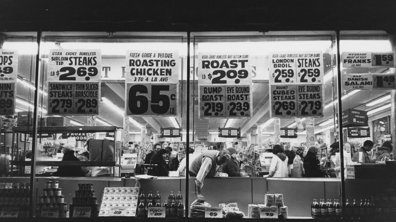 Exterior view of a supermarket display window from the 1980s advertising discounts