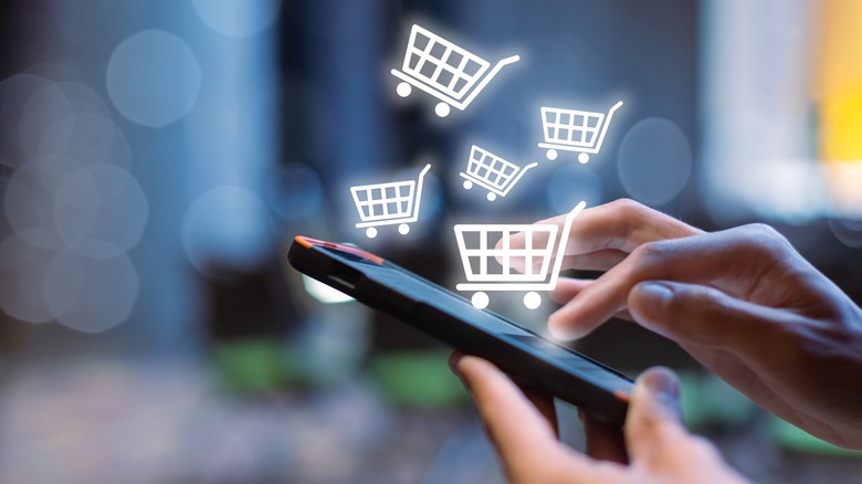 A person uses a smartphone to shop, with shopping cart icons drifting out of it