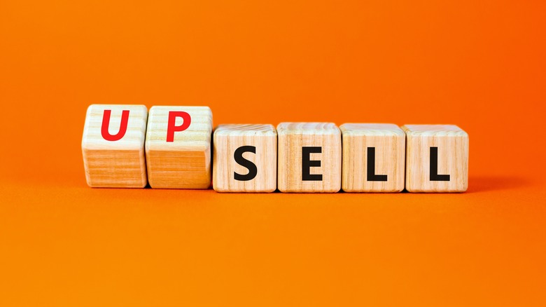 A row of wooden blocks against an orange background, with the word "upsell" spelt out on them