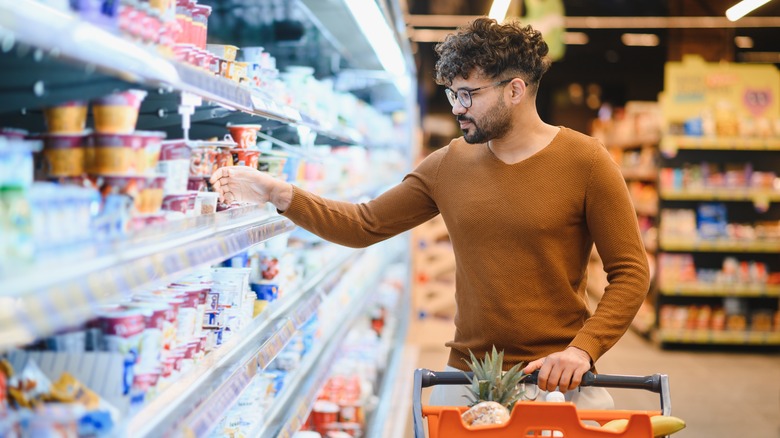 A man reaches for an item inside a supermarket fridge