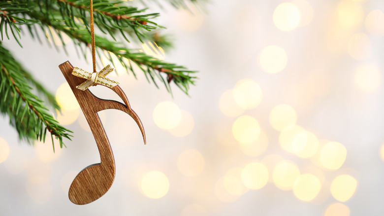 A wooden ornament in the shape of a musical note hangs off a Christmas tree