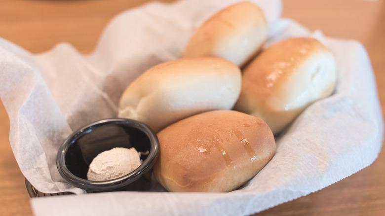 A close up image of a basket of Texas Roadhouse rolls and honey cinnamon butter
