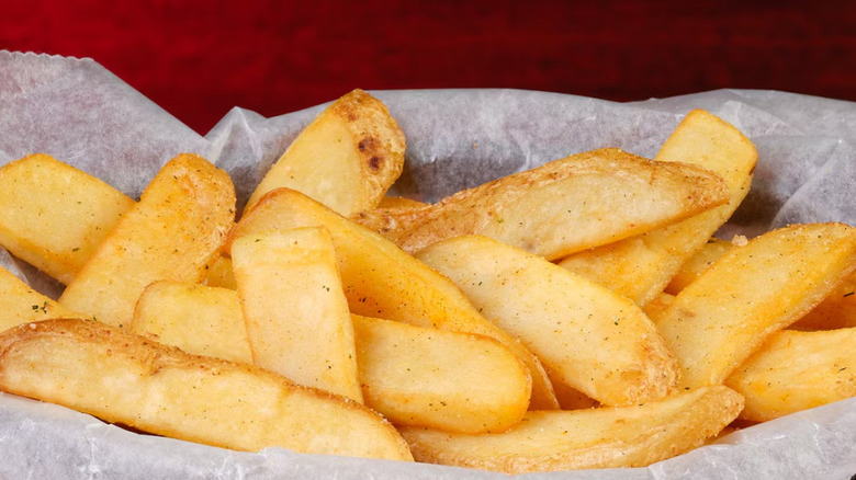 Close up image of Texas Roadhouse steak fries in a basket against a red background