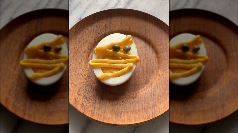 Mummy-styled deviled egg on a wood plate