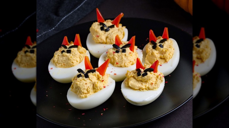 Devil-looking deviled eggs on a black plate