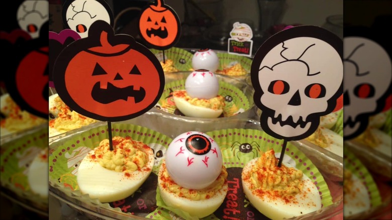 Platter lined with Halloween cupcake liners holding deviled eggs with cupcake toppers in them