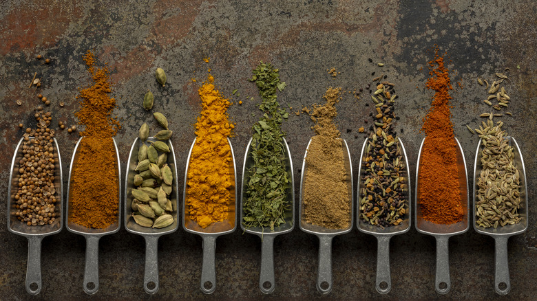 Spices in measuring scoops lined up against a dark surface