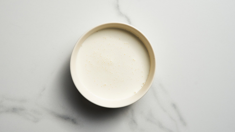 A small container of heavy cream on a white marble surface