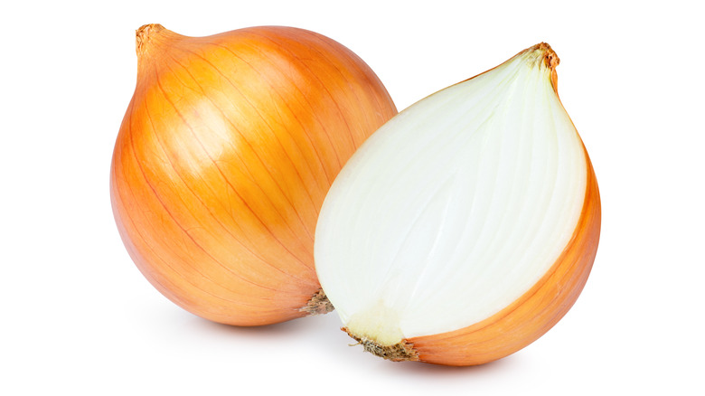 A whole onion and a half onion up close isolated against a white background