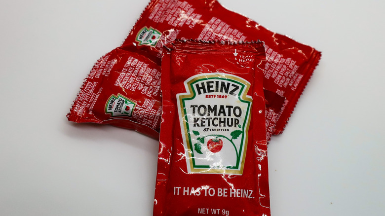 Three Heinz ketchup sachets on a white table