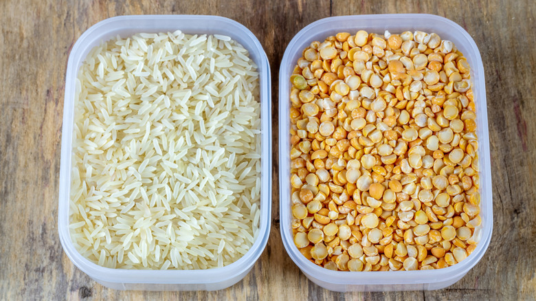 Plastic containers full of rice and lentils on a wooden table