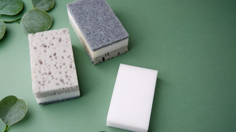 Three kitchen sponges on a green table