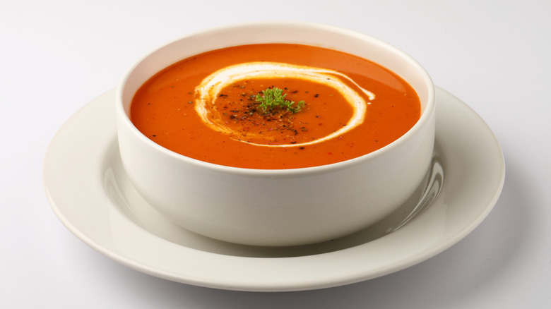 A bowl of tomato soup, with a swirl of cream in it