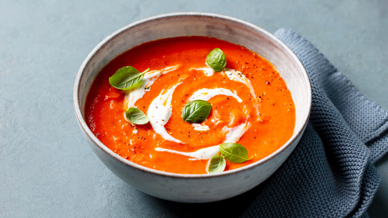 Tomato soup with cream and basil leaves