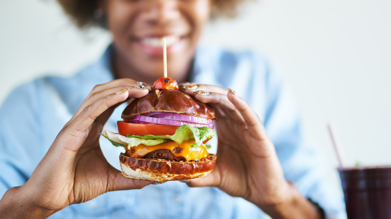 woman eating pretzel bun burger