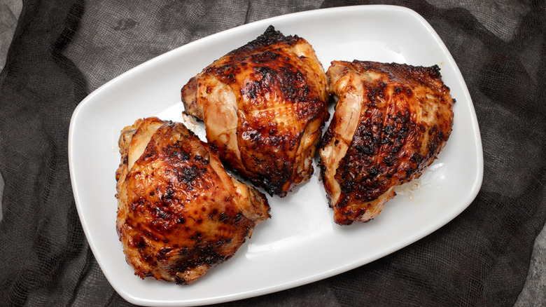 Chicken thighs rest on a plate after being cooked