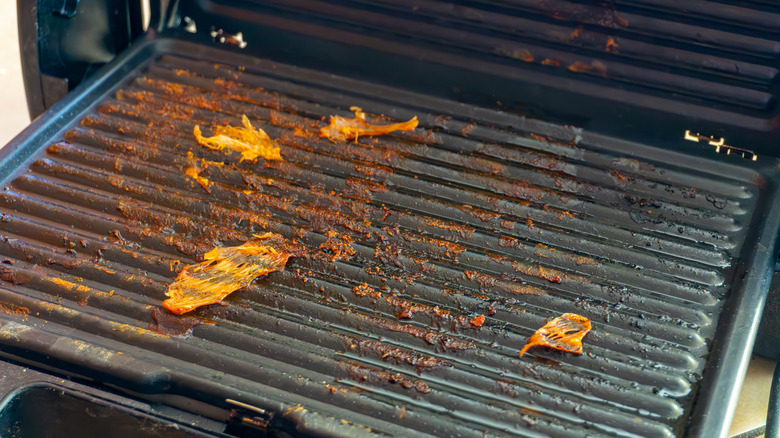 Chicken skin and meat burnt onto a grill after  being cooked at too high a temperature