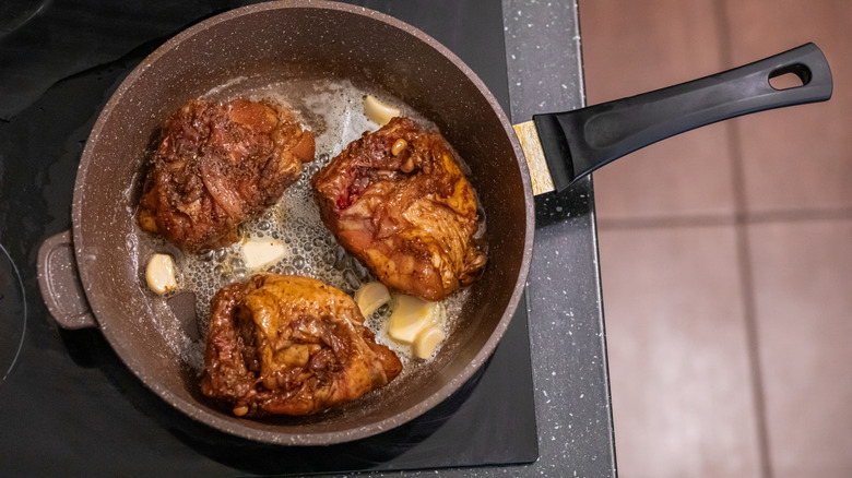 Chicken thighs being cooked incorrectly with skin side up in a frying pan