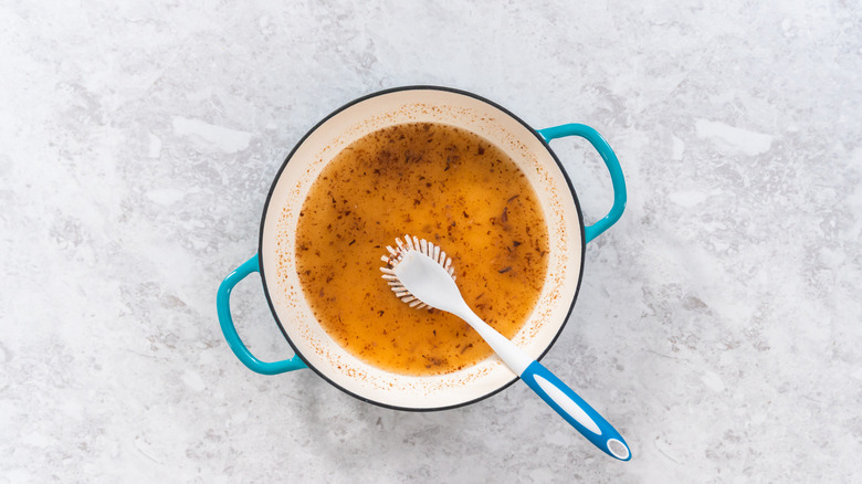 A dirty Dutch oven with a scrubber on a marble table