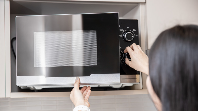 A woman using a microwave