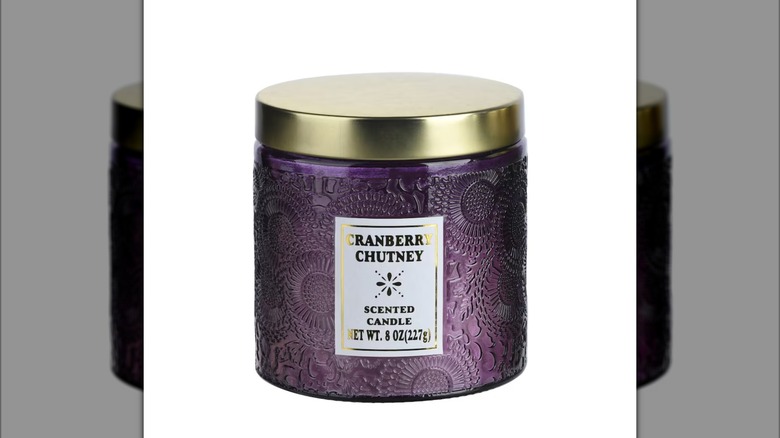 A cranberry chutney scented candle in a purple glass jar
