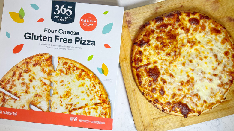 The gluten free four cheese on a cutting board next to its box