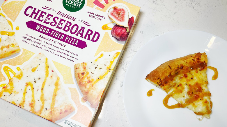 A slice of the Italian cheeseboard pizza drizzled with sauce next to the box