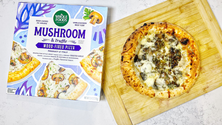 The mushroom and truffle pizza on a cutting board next to the box