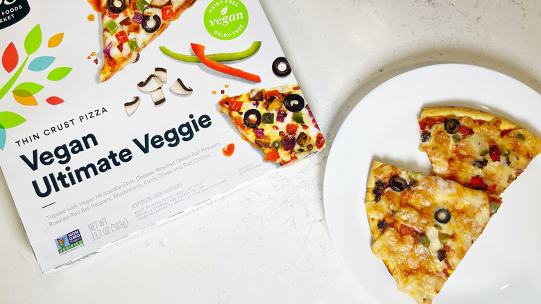 Two slices of the vegan pizza on a white plate next to the box