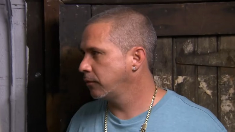 A man in a blue t-shirt looks off-camera