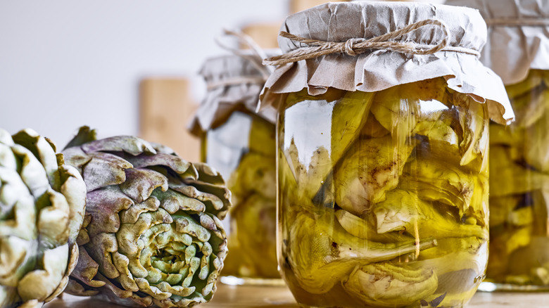 artichokes in jar with artichokes on table