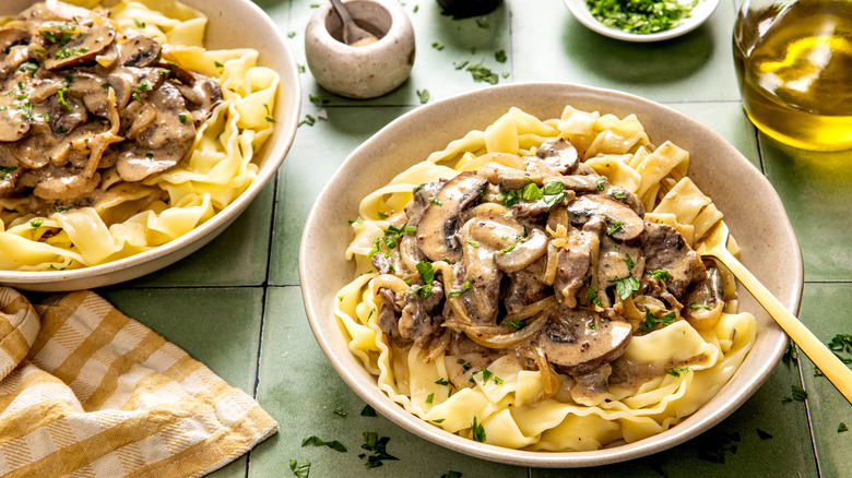 Overhead view of bowls of Beef Stroganoff on tiled countertop