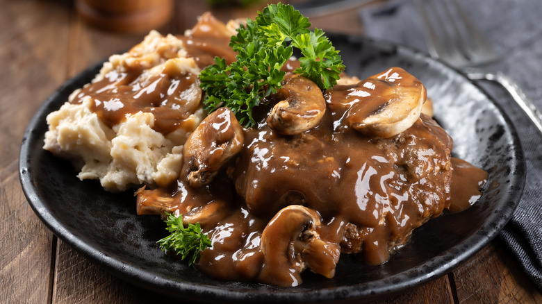 Close-up of a plate of Salisbury steak with mashed potatoes and gravy