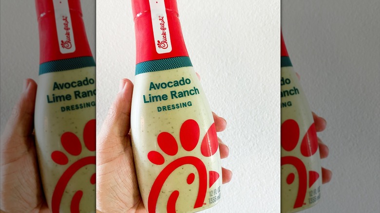 A hand holding a bottle of Avocado Lime Ranch dressing from Chick-Fil-A