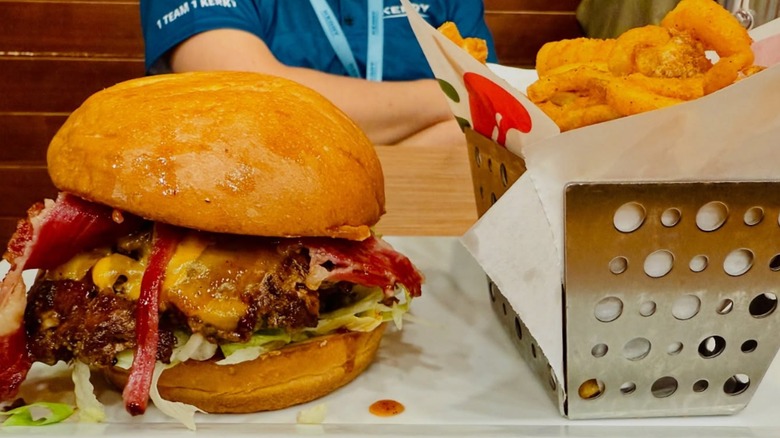 A close-up of a huge bacon cheeseburger and a basket of onion rings from Chili's