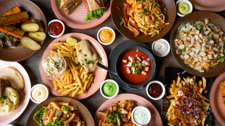 Plates of restaurant food and condiment cups arranged on a table