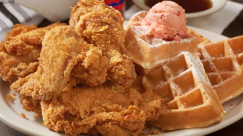 A huge plate of fried chicken and waffles with strawberry butter at a diner