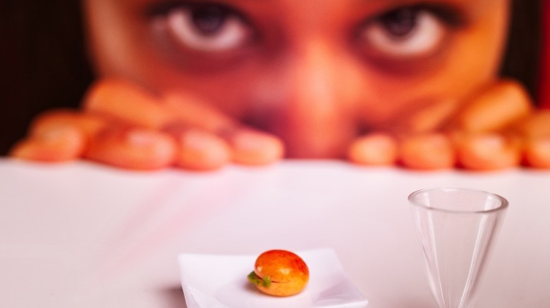 Young woman looking with surprise at a tiny portion of food served on a small plate