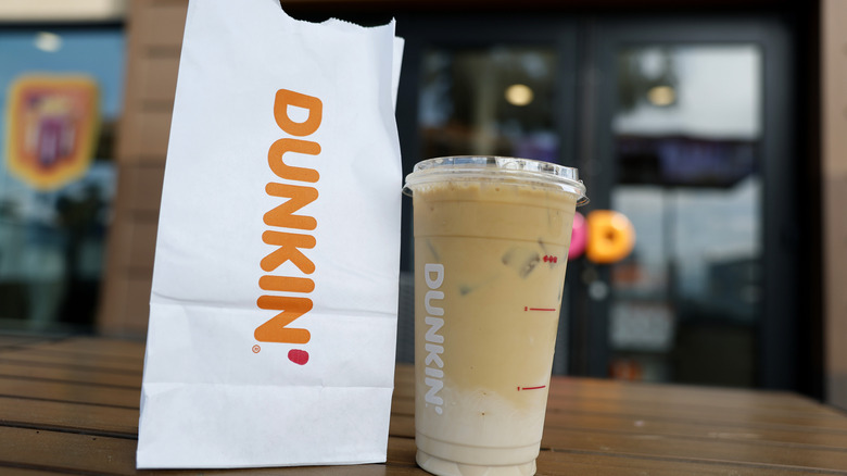 A bag of Dunkin' food sits next to an iced coffee
