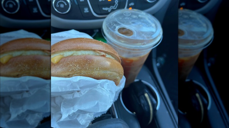 A Dunkin' egg and cheese bagel and an iced coffee, with a car dashboard in the background