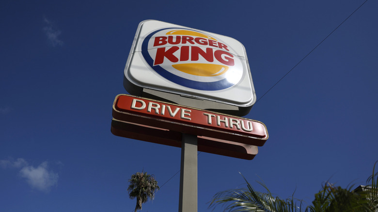 A view of a sign outside a Burger King, against a blue sky