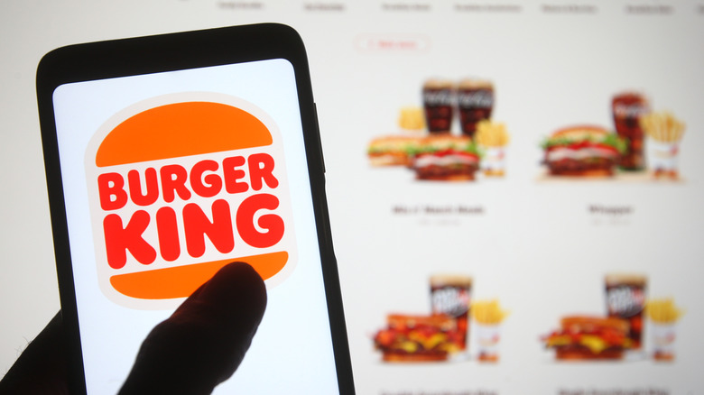 A Burger King app icon is displayed on a smartphone, with the Burger King menu in the background