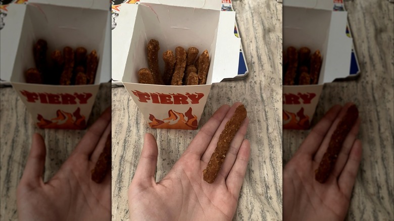 A hand holds a BK Chicken Fry, indicating its small size, next to a carton of Chicken Fries