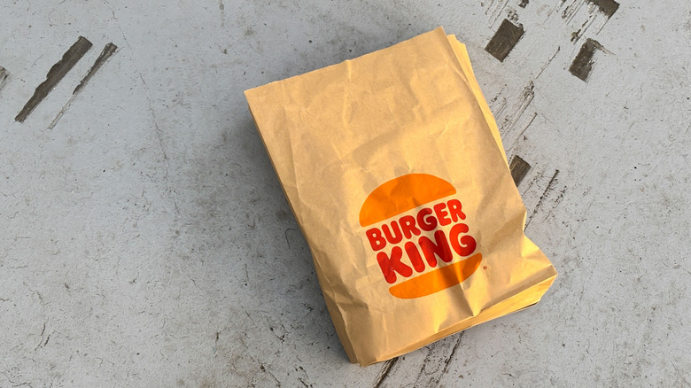 A paper Burger King bag is seen against a detailed background